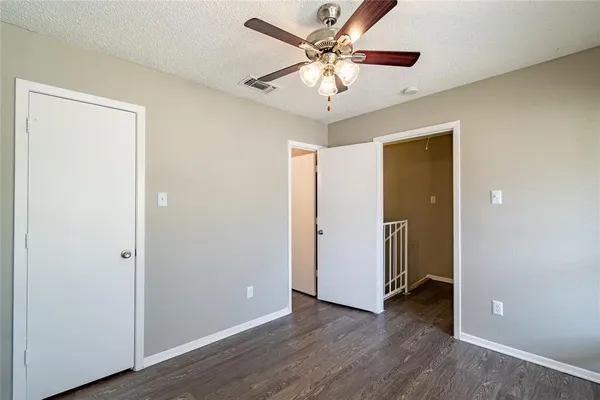 an empty room with wooden floor and a ceiling fan