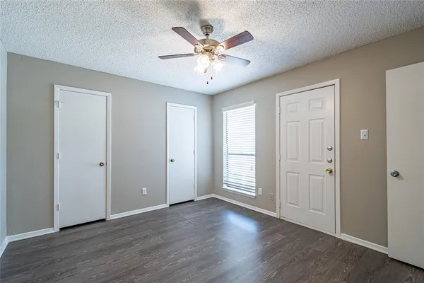 an view of an empty room with wooden floor and a ceiling fan