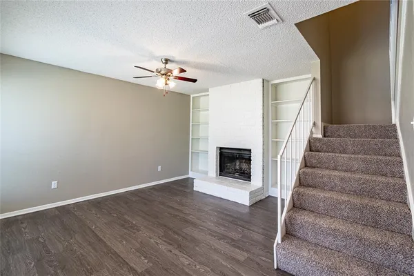 a view of an empty room with wooden floor and a fireplace