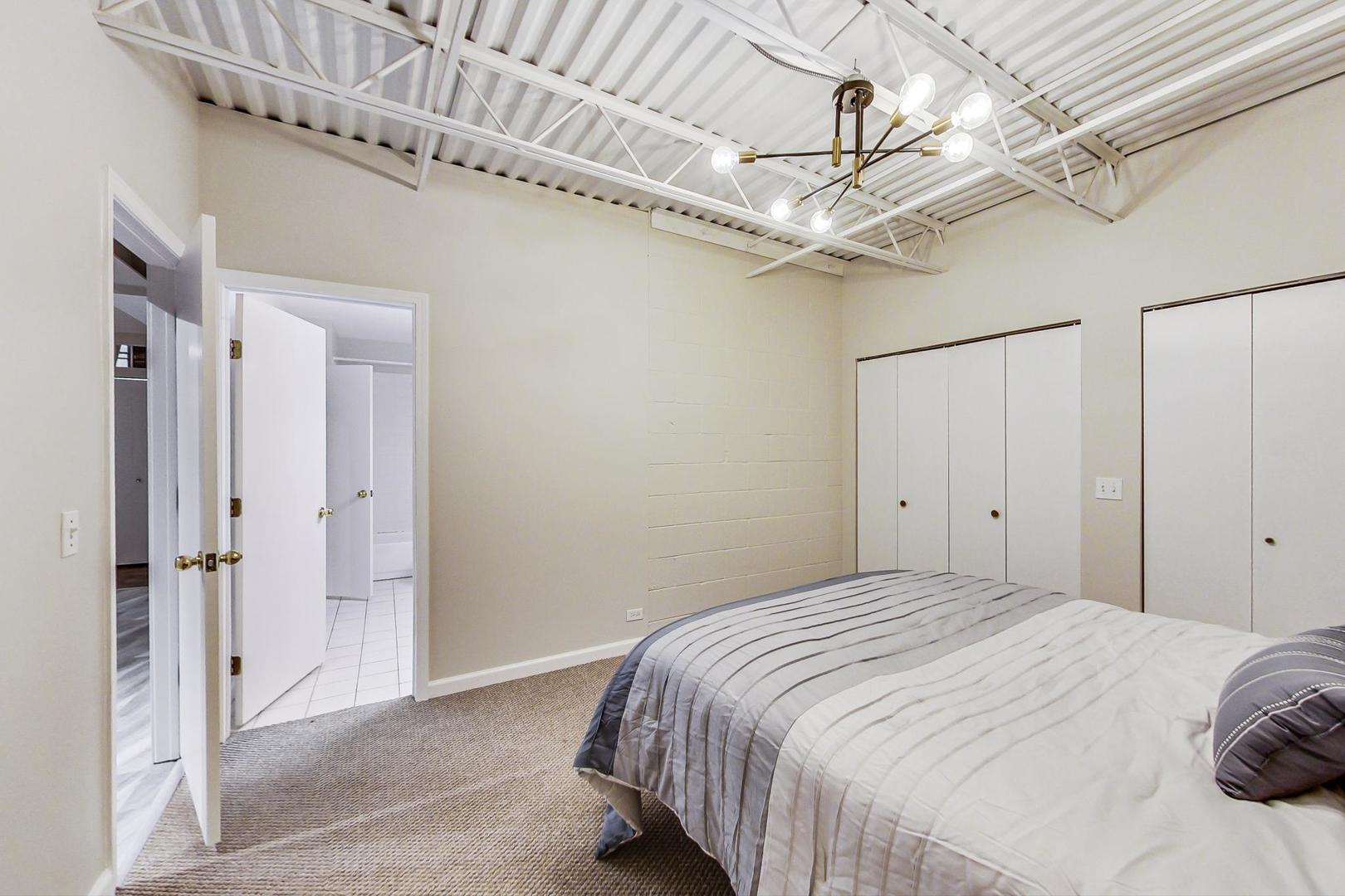 2101 West Rice Street, Unit 103 Chicago, IL 60622 - Photo 16 of 44 a bedroom with a bed and a chandelier
