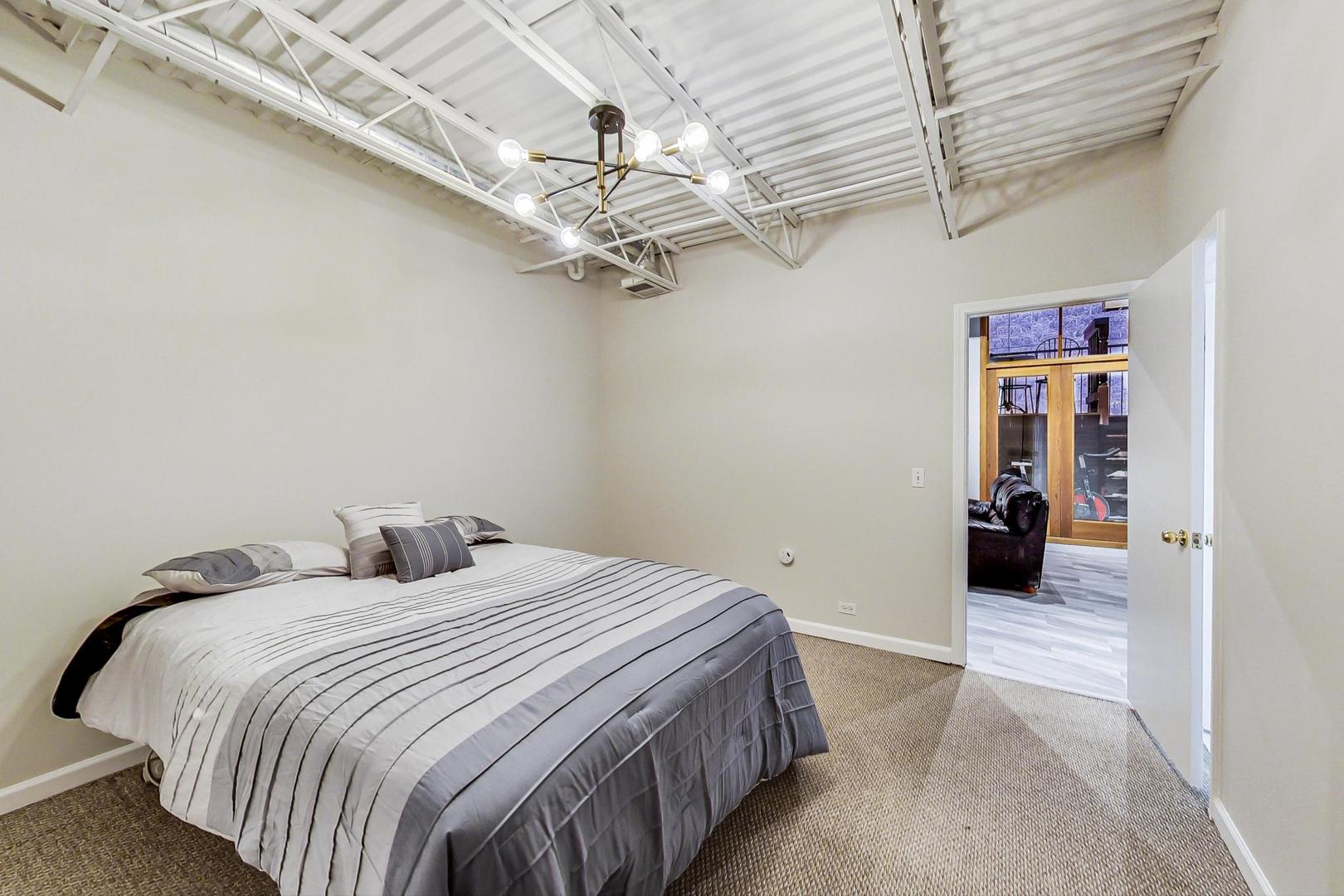 2101 West Rice Street, Unit 103 Chicago, IL 60622 - Photo 17 of 44 a bedroom with a large bed and a chandelier