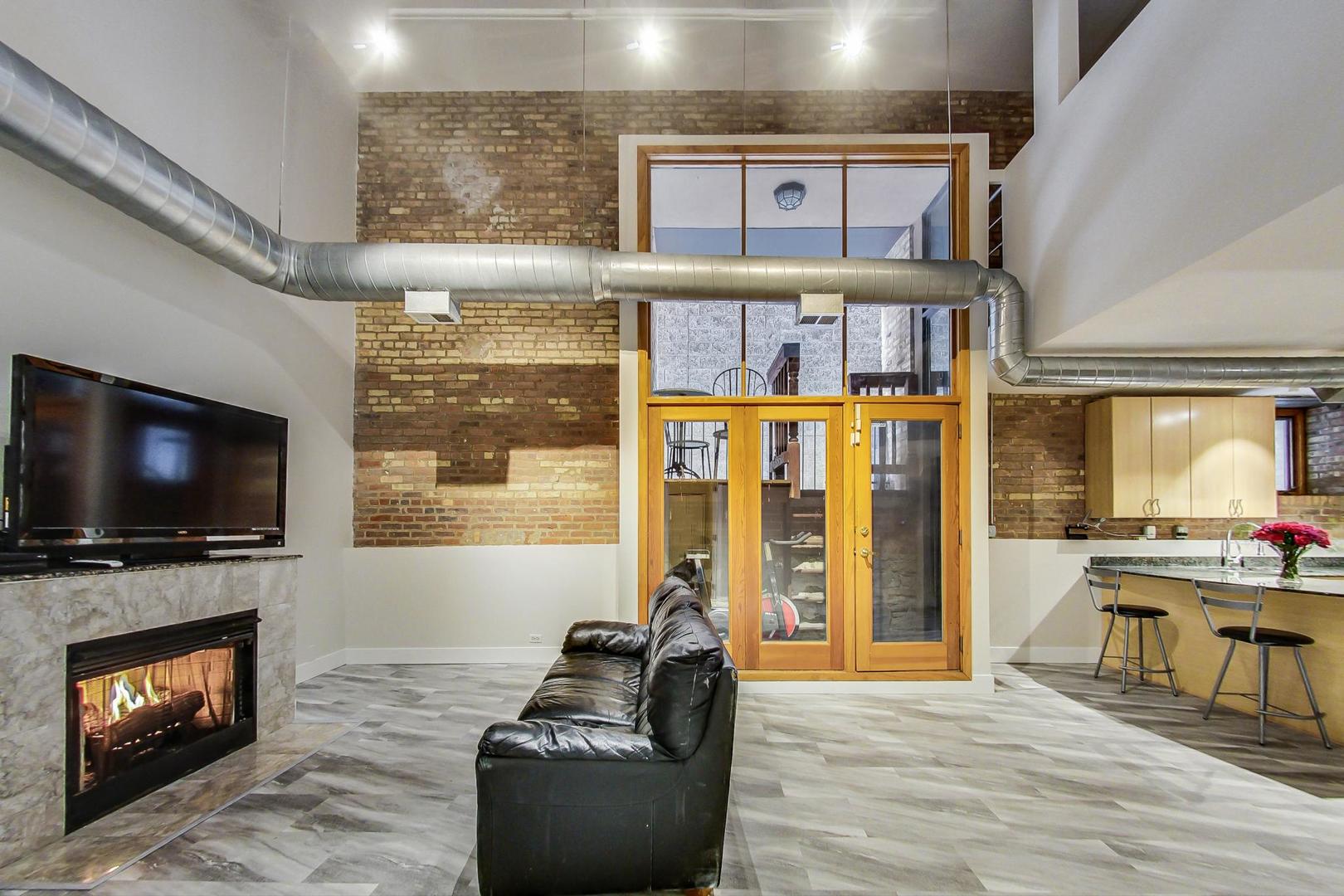 2101 West Rice Street, Unit 103 Chicago, IL 60622 - Photo 8 of 44 a living room with furniture a flat screen tv and a fireplace