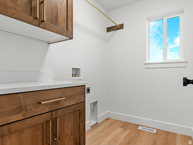1267 West 2350 South Perry, UT 84302 - Photo 23 of 35 Laundry space featuring wood-finish cabinetry with brass hardware, a white countertop, and wood-finish flooring