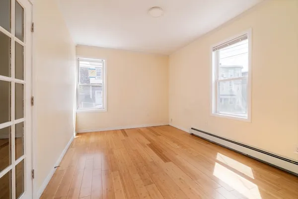 a view of an empty room with wooden floor and a window