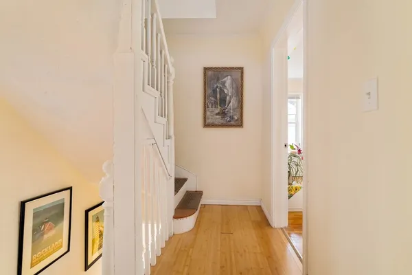 a view of a hallway with wooden floor and a bathroom