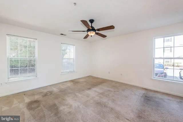 an empty room with windows and fan