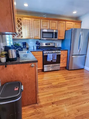 a kitchen with stainless steel appliances wooden cabinets a stove a sink and a microwave