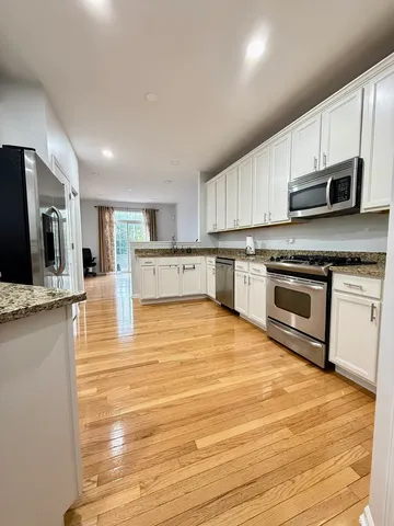 a large kitchen with stainless steel appliances granite countertop a stove a sink dishwasher and a microwave oven on the wooden floor