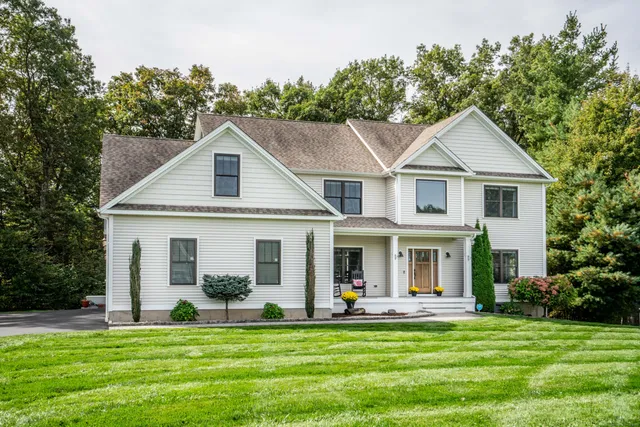 a front view of a house with a garden and trees