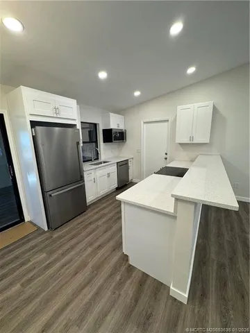 a kitchen with a refrigerator sink and wooden floor