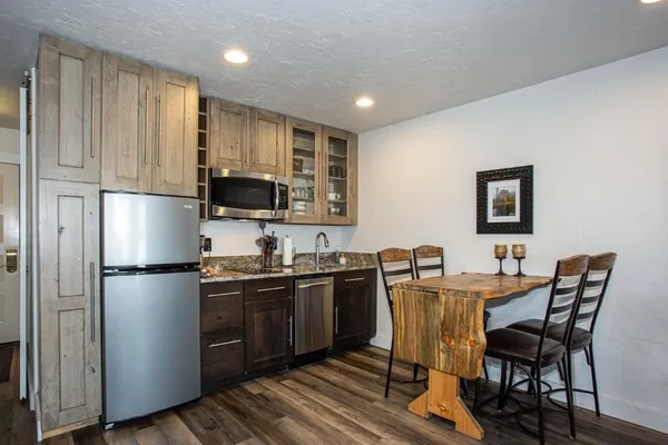 a kitchen with stainless steel appliances granite countertop a refrigerator a sink a stove a dining table and chairs
