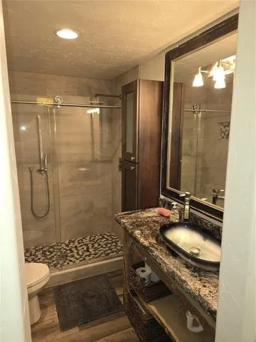 a bathroom with a sink vanity granite toilet and shower
