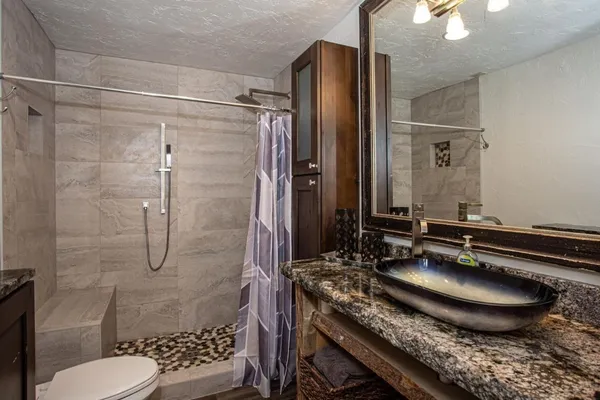 a bathroom with a granite countertop sink a toilet and shower
