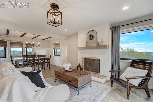 3405 Spaatz Road Monument, CO 80132 - Photo 15 of 47 Living room featuring beam ceiling, light hardwood / wood-style flooring, and an inviting chandelier