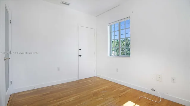 a view of empty room with window and wooden floor