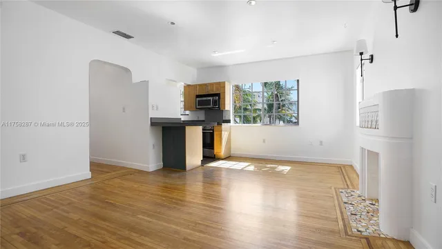 a view of a kitchen with a refrigerator a stove top oven and a wooden floor
