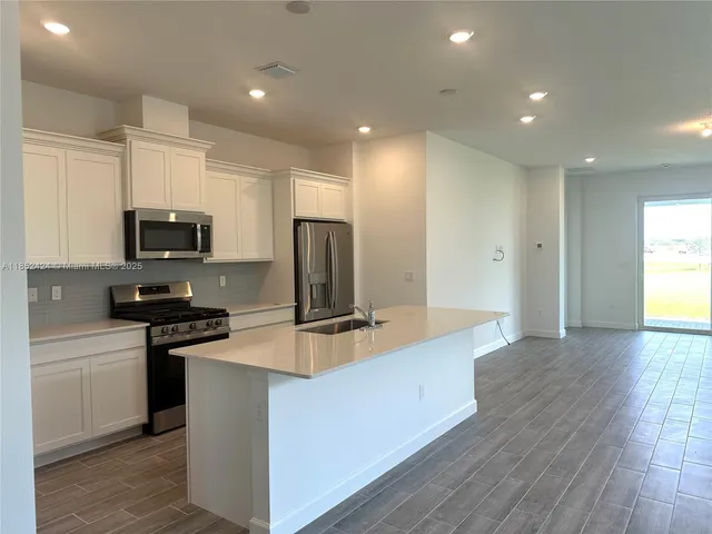 a kitchen with stainless steel appliances a stove a sink a refrigerator a microwave a sink and cabinets