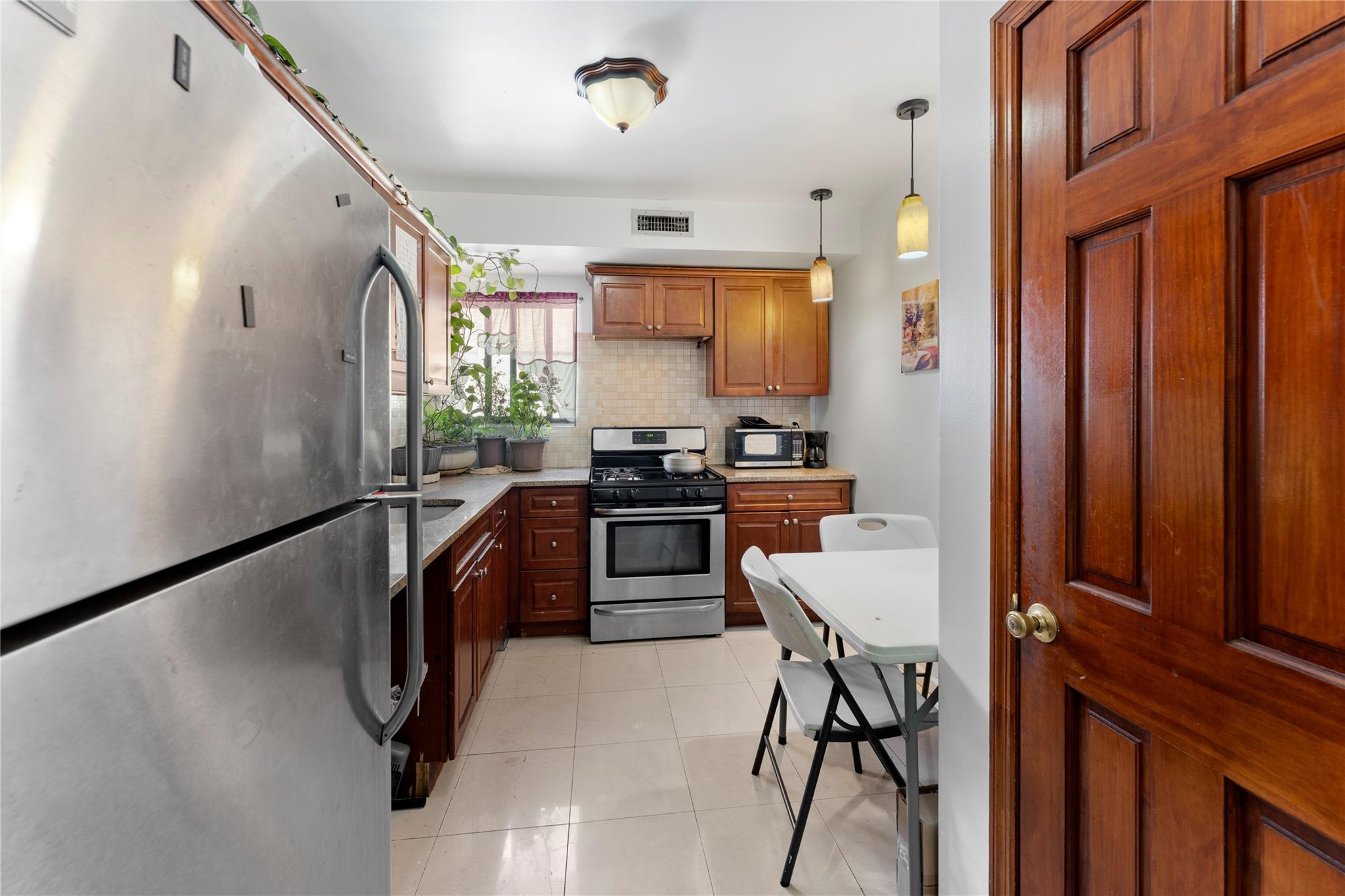 848 Morris Park Avenue Bronx, NY 10462 - Photo 6 of 22 a kitchen with a table chairs refrigerator and cabinets
