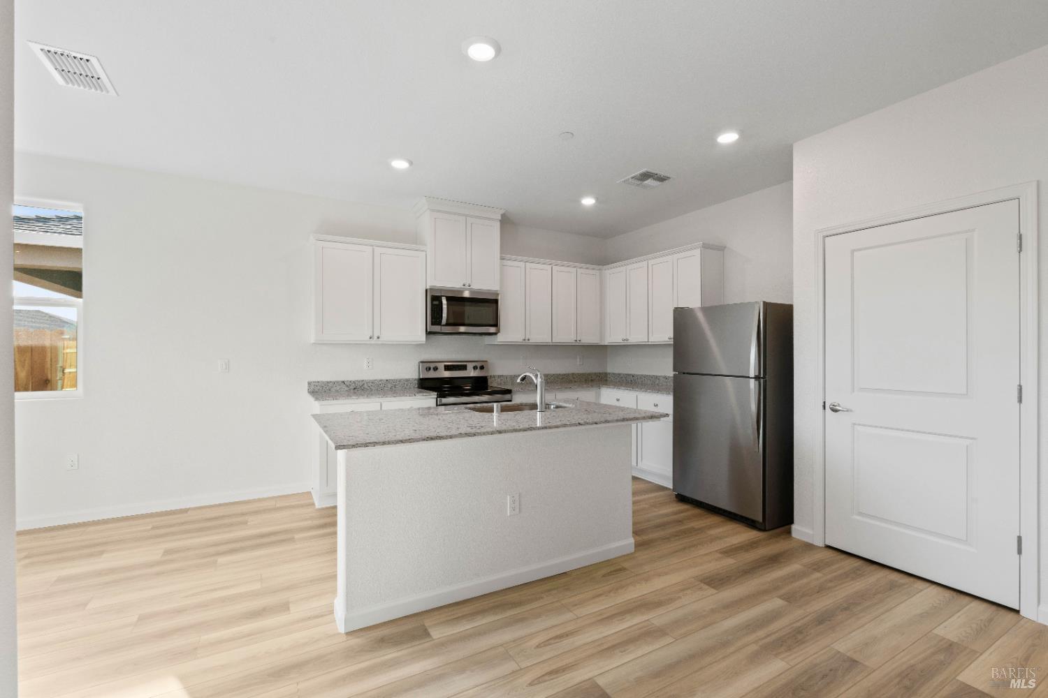 2231 Park Place Rio Vista, CA 94571 - Photo 5 of 12 a kitchen with stainless steel appliances a refrigerator stove a sink and white cabinets with wooden floor