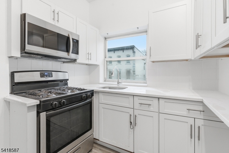 5 Elm Street, Unit 3 Newark, NJ 07102 - Photo 8 of 15 a kitchen with cabinets stainless steel appliances and wooden floor