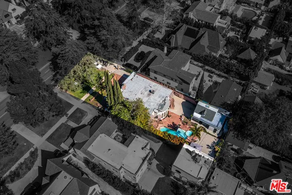 an aerial view of a house with a yard and a large tree