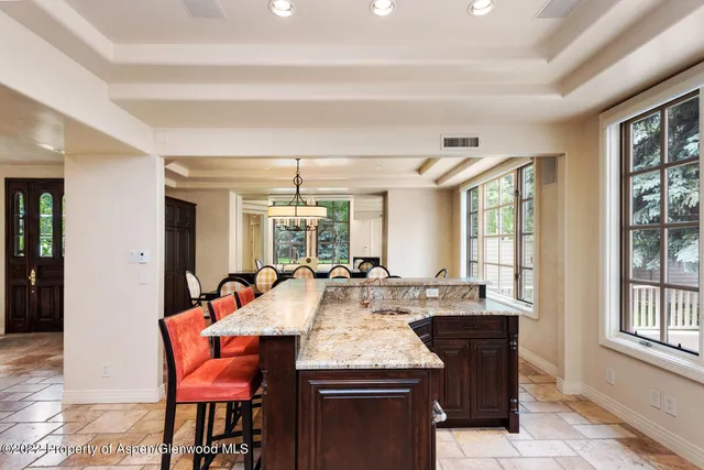 a dining hall with stainless steel appliances granite countertop a stove and a dining table chair