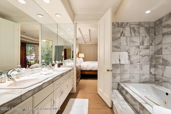 a en suite bathroom with a double vanity sink a mirror and a bathtub