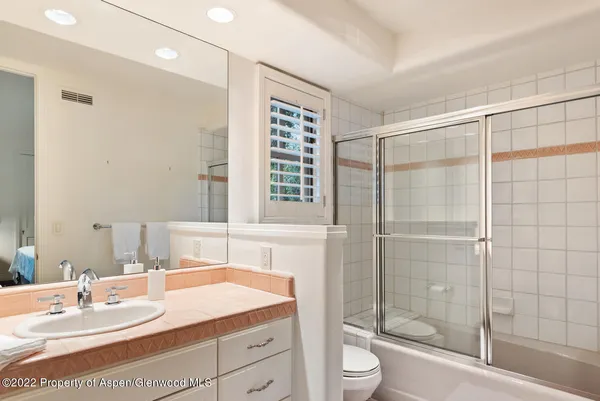 a bathroom with a granite countertop sink a toilet and shower