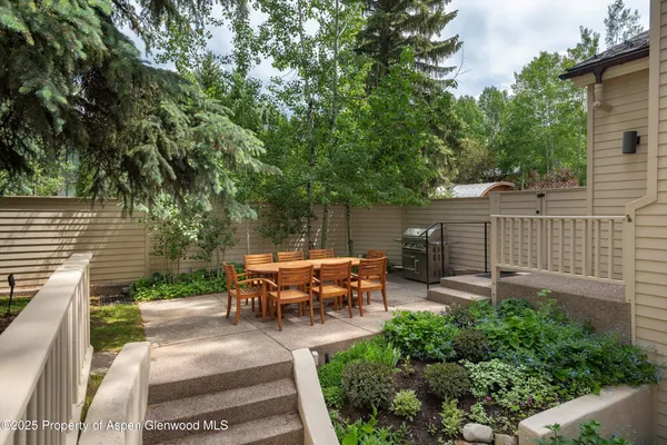 a view of a patio with table and chairs potted plants and large tree