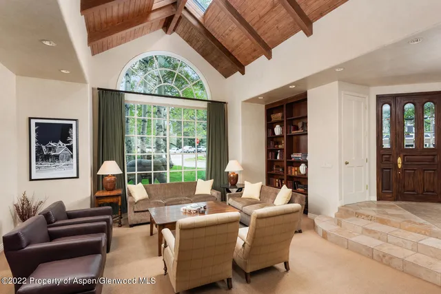 a living room with furniture large window and cabinet