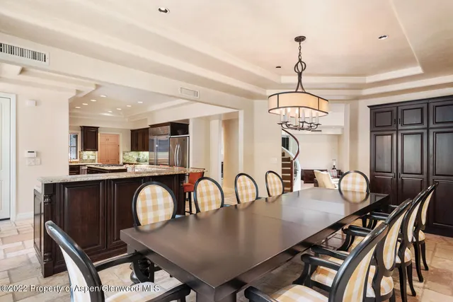 a dining room with wooden floor a chandelier a wooden table and chairs