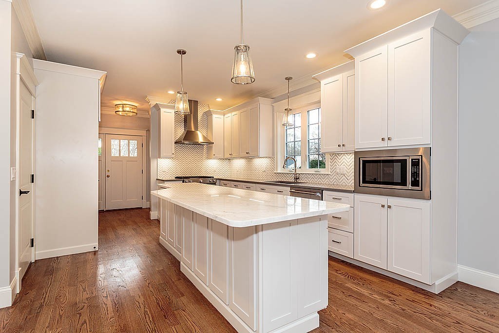 8 Cleveland Road, Unit A Winchester, MA 01890 - Photo 6 of 26 a kitchen with kitchen island granite countertop a sink cabinets and wooden floor