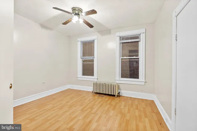a view of empty room with wooden floor and fan
