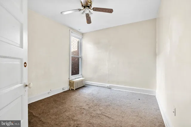 an empty room with a ceiling fan and a window
