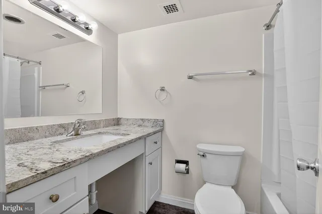 a bathroom with a granite countertop sink toilet and shower