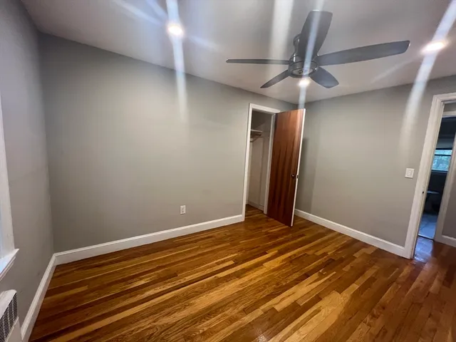en empty room with wooden floor and fan