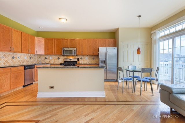 1270 Georgetown Way Vernon Hills, IL 60061 - Photo 6 of 25 a kitchen with stainless steel appliances granite countertop a stove a refrigerator a microwave oven with a dining table and chairs with wooden floor