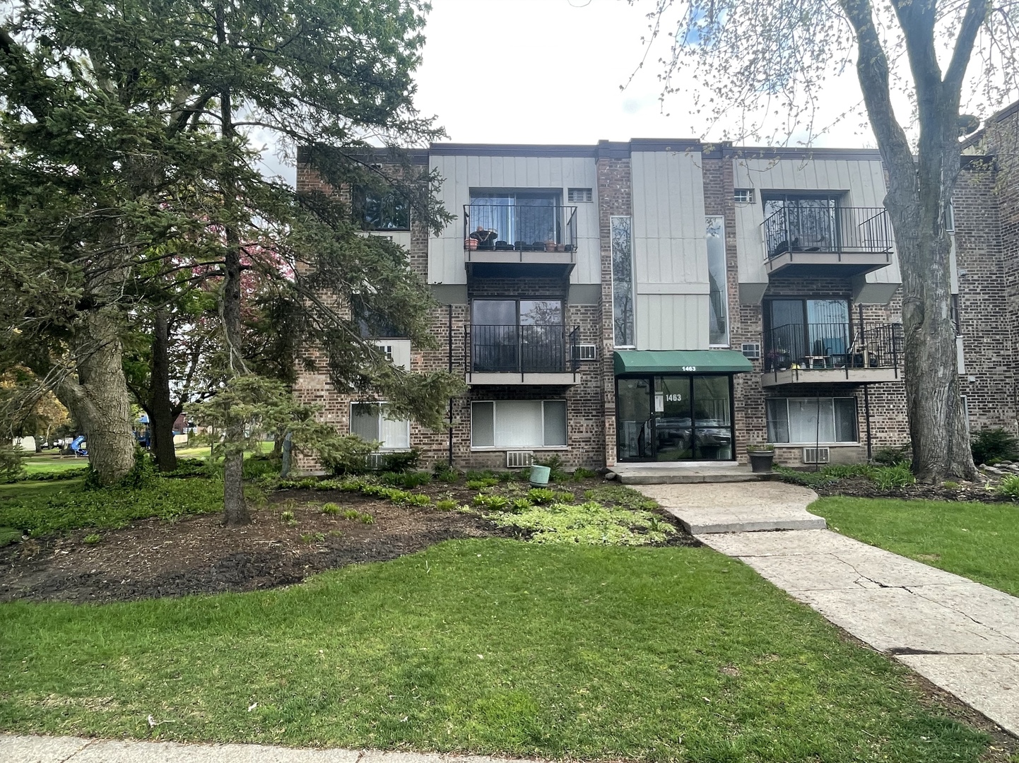 a brick house with a small yard and a large tree