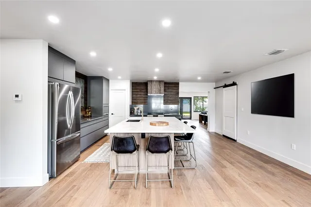 a kitchen with stainless steel appliances kitchen island granite countertop a refrigerator and a stove top oven