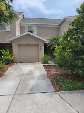 a front view of a house with garage and plants