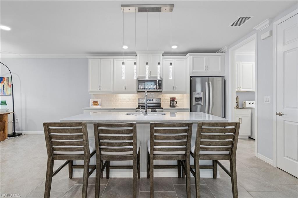 14618 Edgewater Circle Naples, FL 34114 - Photo 6 of 30 Kitchen with stainless steel appliances, white cabinetry, and light tile patterned floors