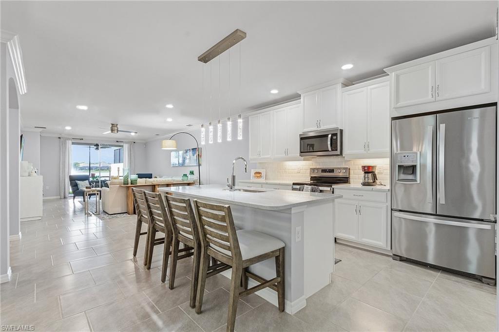 14618 Edgewater Circle Naples, FL 34114 - Photo 8 of 30 Kitchen featuring ceiling fan, stainless steel appliances, and white cabinets