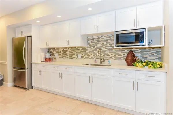 a kitchen with stainless steel appliances kitchen island granite countertop a refrigerator and a sink