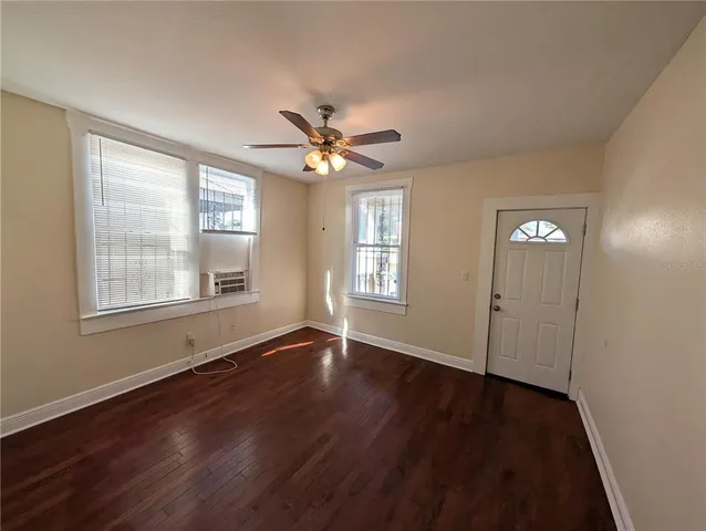 a view of an empty room with wooden floor and a window