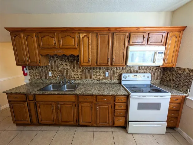 a kitchen with granite countertop a sink stove and cabinets