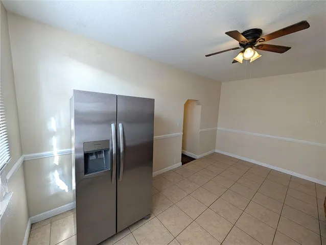 a view of a refrigerator in kitchen and an empty room