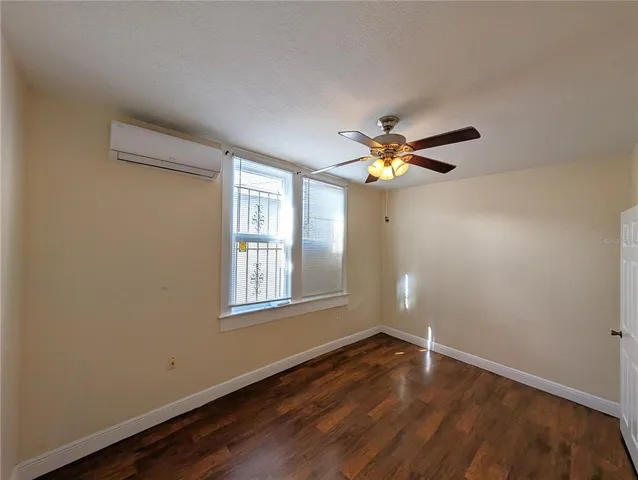 a view of empty room with wooden floor and fan