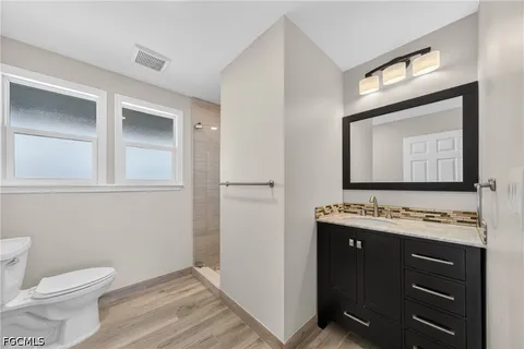a bathroom with a granite countertop toilet sink and mirror