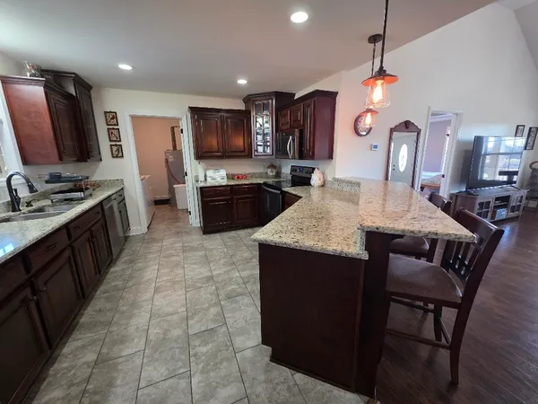 a kitchen with stainless steel appliances kitchen island granite countertop a table chairs and a refrigerator