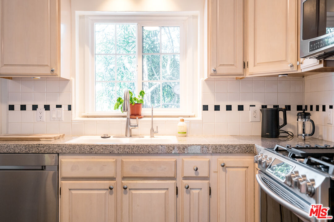 5849 Goodland Avenue Valley Village, CA 91607 - Photo 6 of 25 a kitchen with granite countertop a sink stainless steel appliances white cabinets and a window